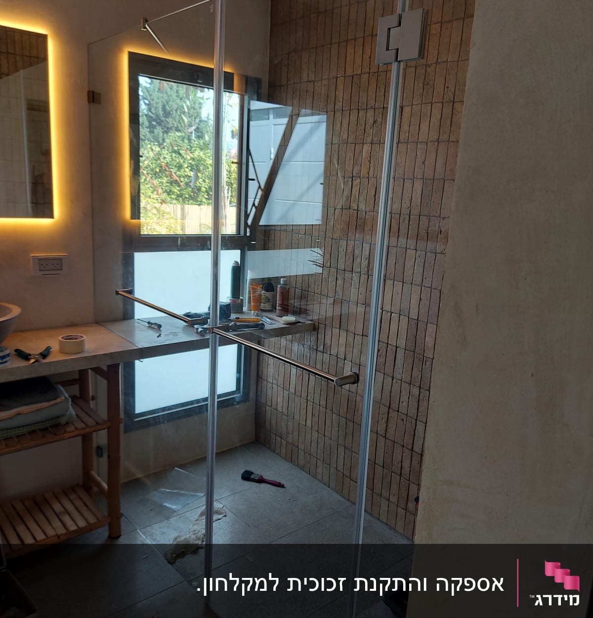 מקלחון זכוכית עם דלת פתוחה ומוצרים על המדף